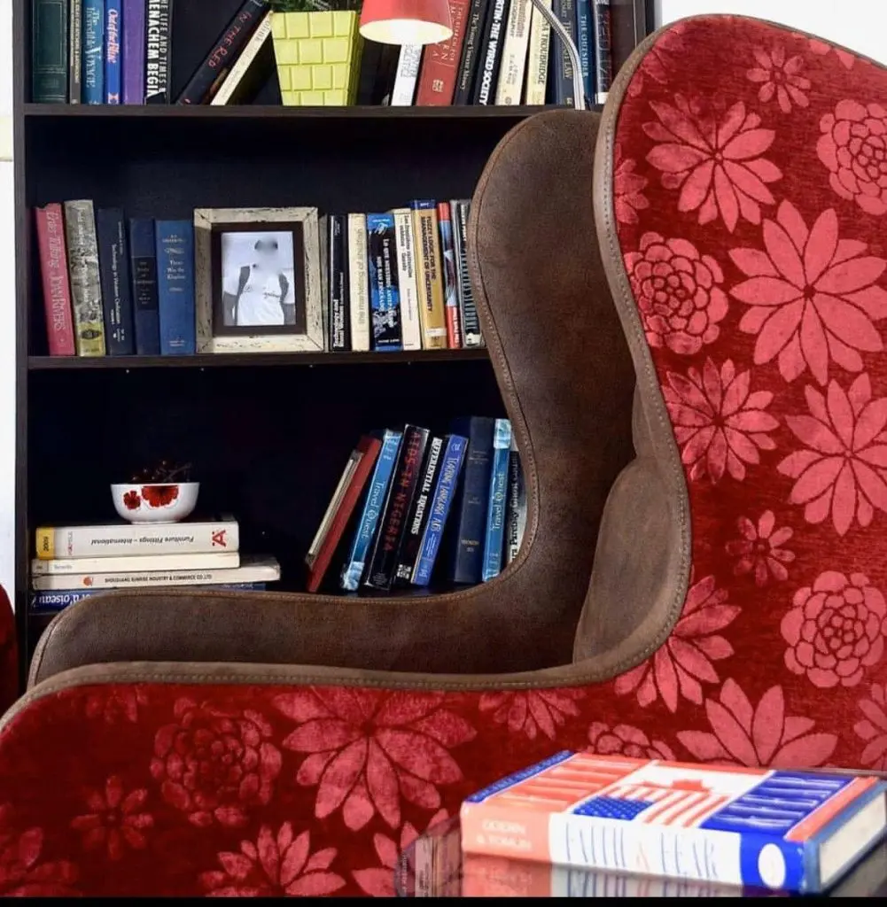 Red floral wingback armchair in front of a bookshelf filled with books